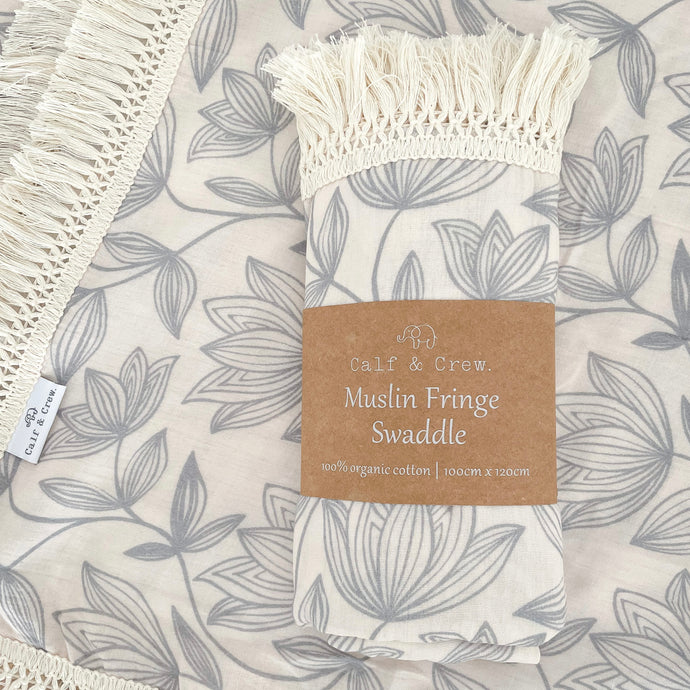 two organic cotton fringe swaddles in waterlily, one laying flat with the other folded in Calf & Crew packaging