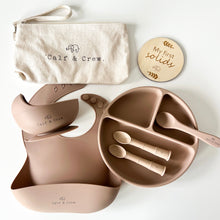 Load image into Gallery viewer, Beige pouch with Calf &amp; Crew logo, a wooden plaque engraved with &quot;my first solids&quot;, a suction bowl on a  silicone bib, a divided plate with three spoons in latte colour
