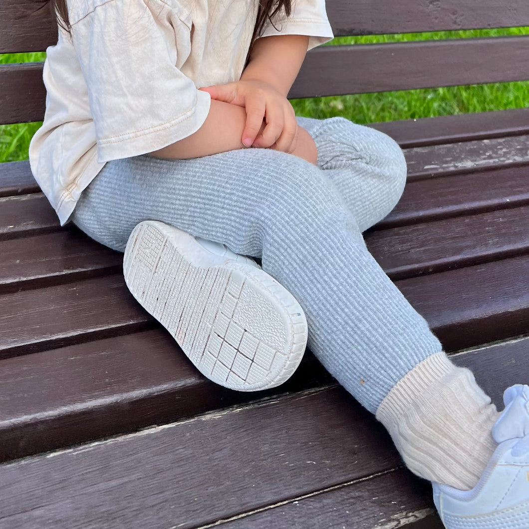 a child sitting on a park bench wearing the ribbed thick slim fit leggings in cloudy grey